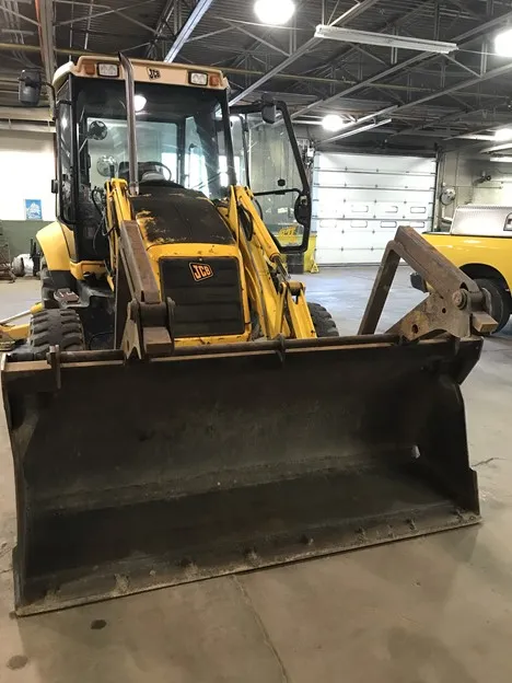 An image showing a front view of a backhoe folding fork attached to a yellow PennDOT construction vehicle.